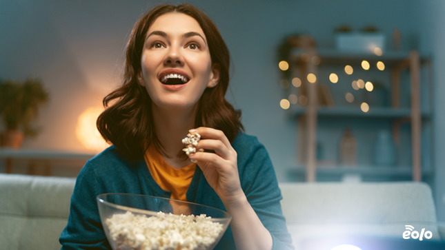 ragazza mangia popcorn e guarda tv